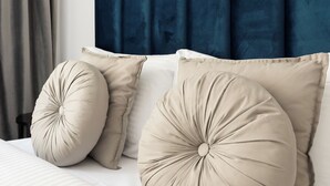 A bedroom with a dark blue headboard, two large beige pillows, and a bed with white bedding. - Plac Politechniki Cosy Studio (Warszawa)