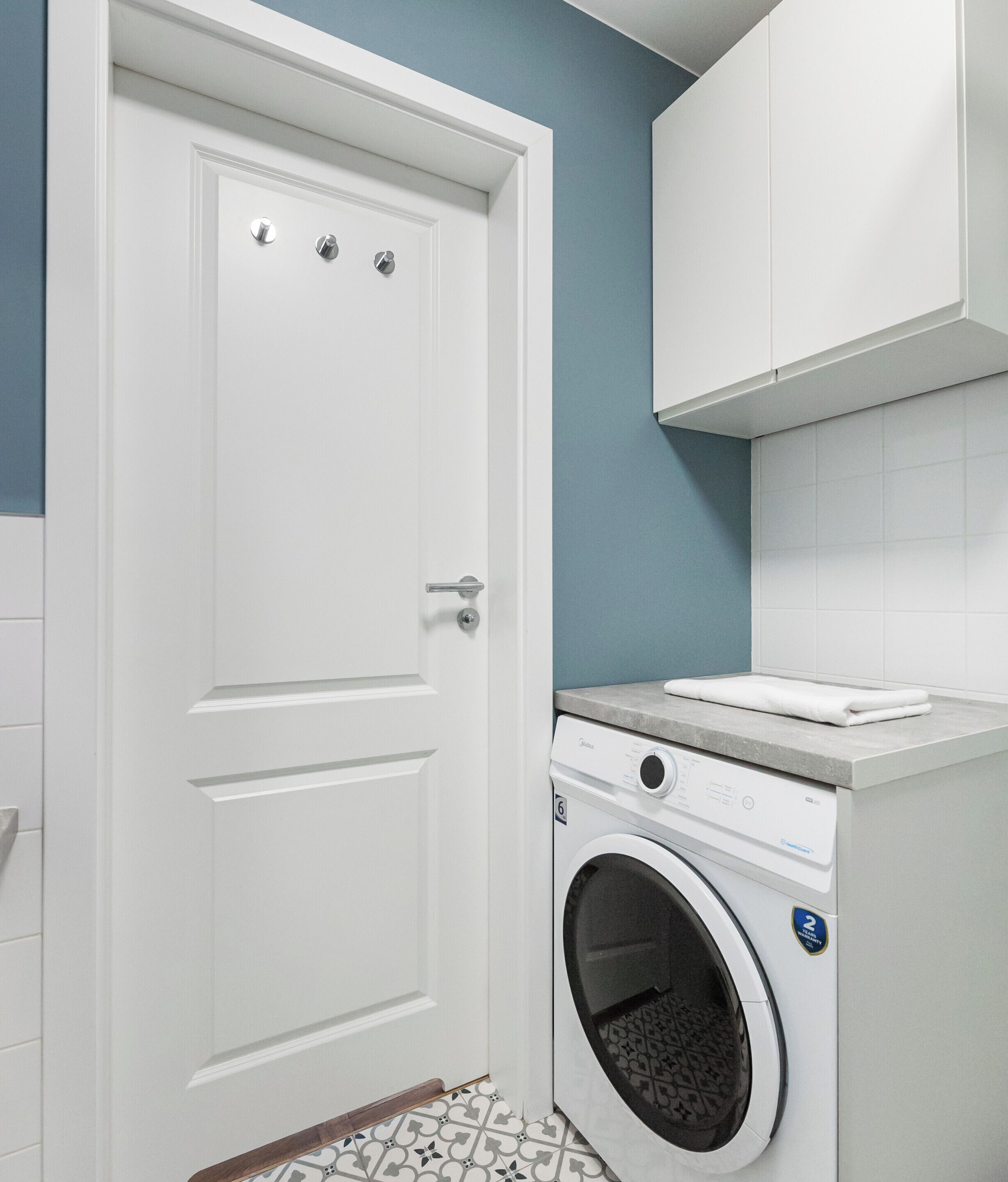 Een wasserette met een witte deur, een wasmachine en een aanrecht.