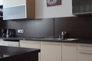 A kitchen with a black countertop, beige cabinets, a stainless steel sink, and a coffee maker.