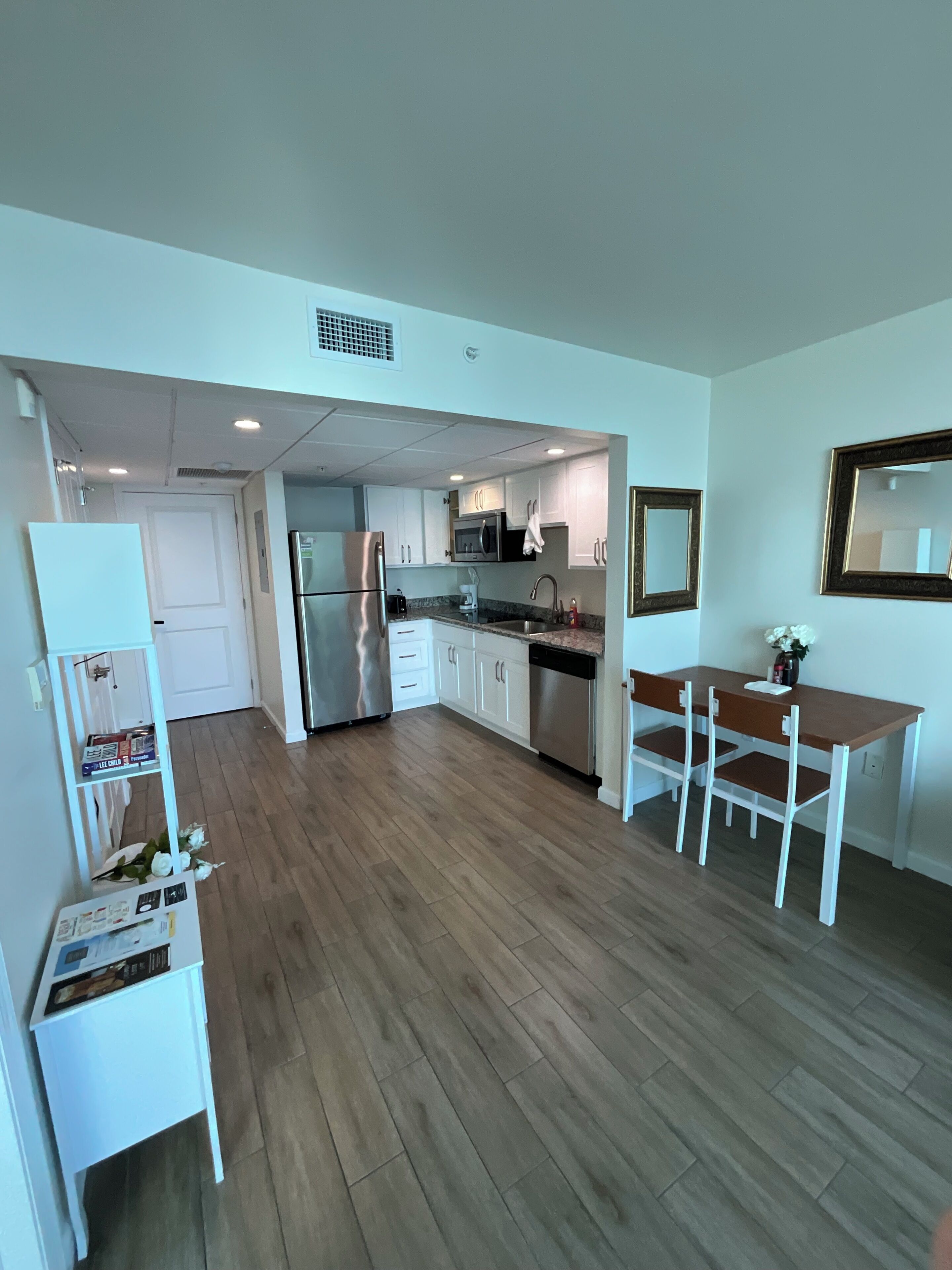 A modern kitchen with white cabinets, stainless steel appliances, and a wooden dining table.