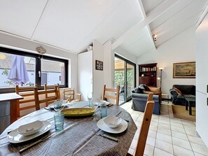 Ein Essbereich mit einem Tisch für vier Personen, einem Bücherregal und einem Sofa in einem modernen Interieur.