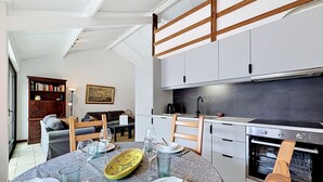 A modern kitchen with white cabinets, a dining table set for four, and a large oven. - Reynaertpark with parking by Interhome (Bredene)