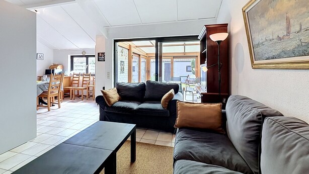 A modern living room with a sofa, a coffee table, and a dining area with chairs and a table. - Reynaertpark with parking by Interhome (Bredene)