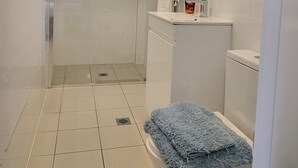 Een moderne badkamer met een douchecabine van glas, een witte wastafel en een toilet.