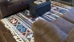 A cozy log cabin interior with a brown sofa, a patterned rug, and a television on a wooden stand. - Cozy cabin in enjoyable Kaw City with WiFi, AC (Kaw City)