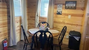 A wooden interior with a round table, four chairs, a fire extinguisher, and a sign that says "House". - Cozy cabin in enjoyable Kaw City with WiFi, AC (Kaw City)