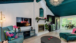 Un ampio soggiorno con camino, una TV che mostra 'NETFLIX' e un'area pranzo con vista.
