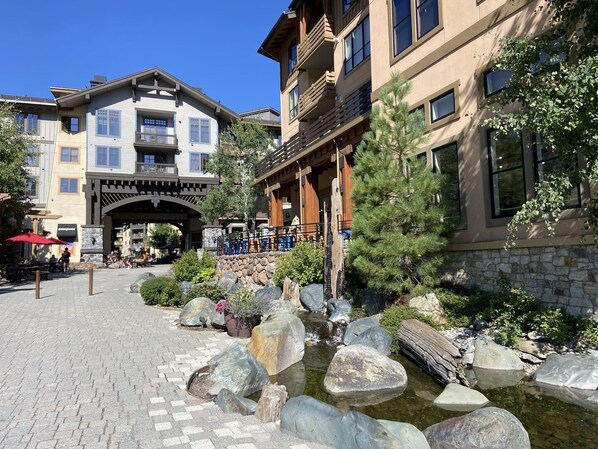 A hotel with a stone facade, a wooden archway entrance, and a landscaped garden with rocks and a small water feature.