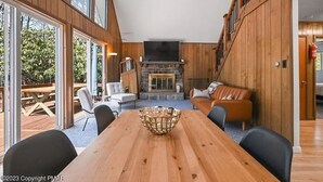 Amplia habitación con una gran mesa de comedor de madera, chimenea de piedra y una zona de estar acogedora con sofá y sillones.
