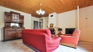 Una sala de estar con un sofá rojo, un mueble de madera, chimenea y televisor.