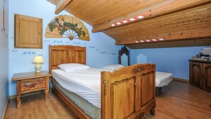 Un dormitorio con una cama de madera, una mesita de noche, un aparador, un espejo y un abanico decorativo en la pared.