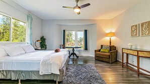 Une chambre à coucher comprenant un lit, un ventilateur de plafond, une table de chevet, une lampe, une chaise et une table.