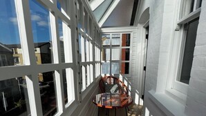 A narrow corridor with white walls and large windows, leading to a small seating area with two chairs and a glass table. - Newly Refurbished w/ River Views (Greater London)