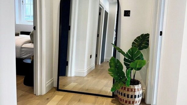 A hallway with a large mirror, wooden flooring, and a potted plant. - Newly Refurbished w/ River Views (Greater London)