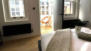 A bedroom with a bed, a radiator, a window, and a door leading to an outdoor area. - Newly Refurbished w/ River Views (Greater London)