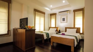 A hotel room with two wooden beds, a wooden desk, a television, and an air conditioning unit. - Thaihome Resort (Bang Kruai)