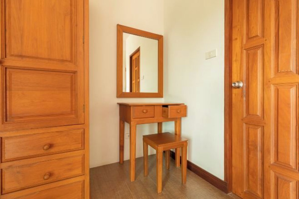 A wooden dresser with drawers, a small table, and a mirror on the wall.