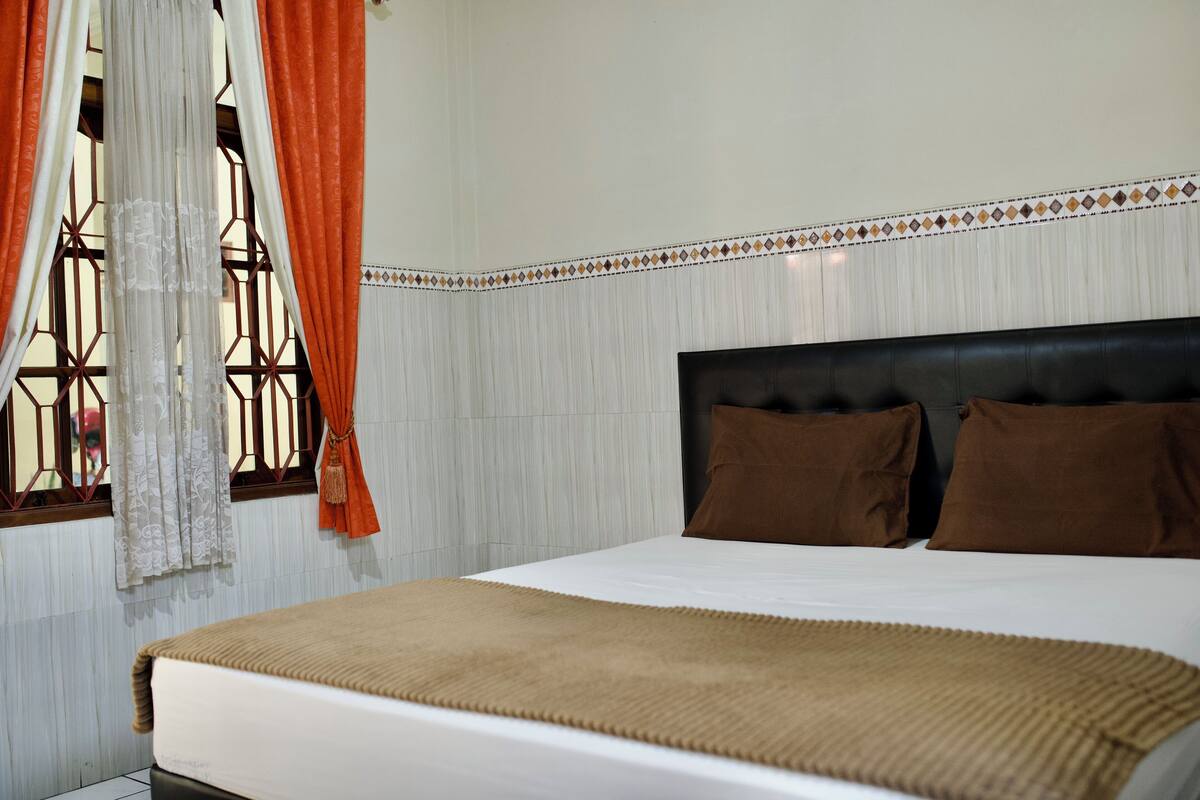 A neatly made bed with a brown blanket, a headboard, and two brown pillows.