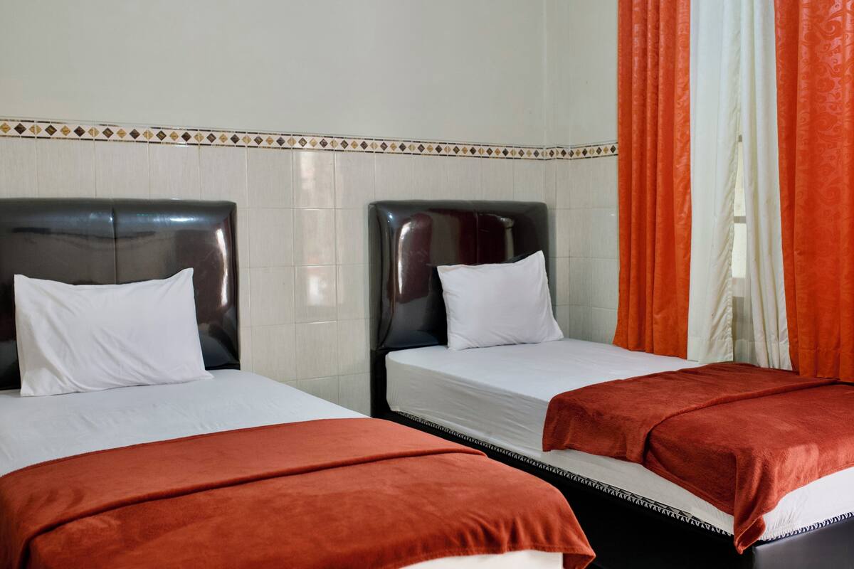 A hotel room with two beds, each with a black headboard and white bedding.