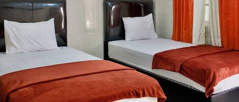A hotel room with two beds, each with a black headboard and white bedding.