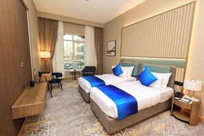 A hotel room with a large bed, a desk, a chair, a nightstand, and a window with curtains. - Premier King Room Near By Al Dana Centre (دبي)