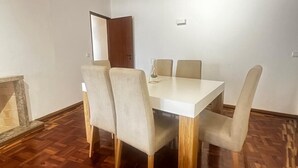 A dining area with a white table and four chairs, a wooden floor, and a door in the background. - João Paulo II - Fátima (Fátima)
