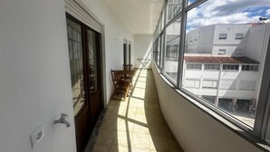 A narrow corridor with a wooden table and chairs, large windows, and a view of buildings outside. - João Paulo II - Fátima (Fátima)