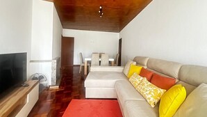 A modern living room with a wooden ceiling, a sofa with patterned cushions, a red rug, and a TV on a wooden stand. - João Paulo II - Fátima (Fátima)