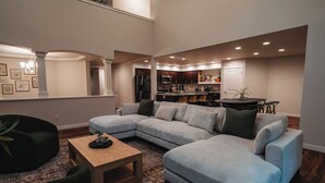 Un salon moderne avec un canapé d’angle, une table basse en bois et un coin repas comprenant une table et des chaises.