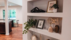 Un intérieur moderne avec des murs blancs, un plancher en bois et une bibliothèque intégrée où sont exposés divers objets décoratifs.