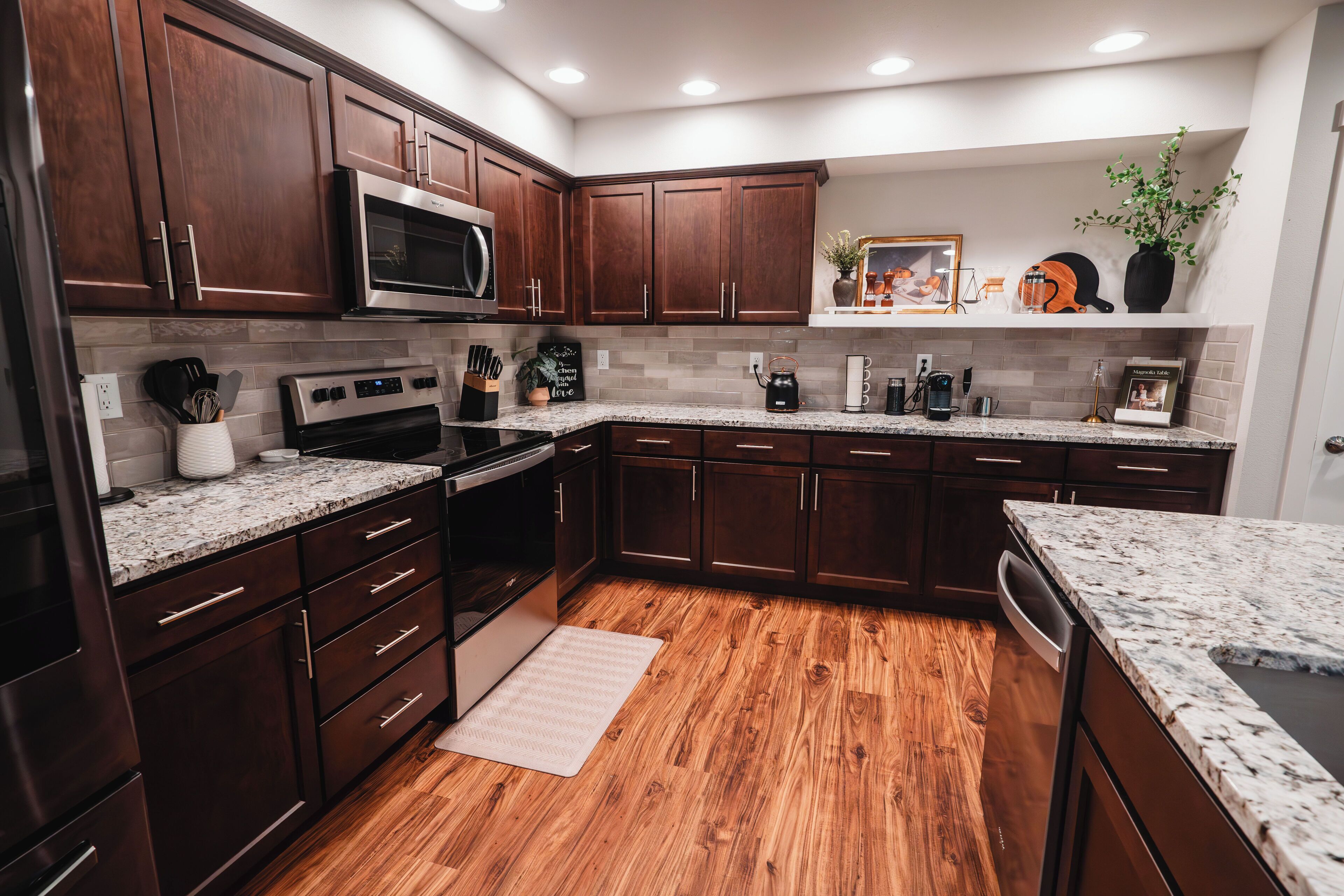 A modern kitchen with dark wood cabinets, stainless steel appliances, and a granite countertop.