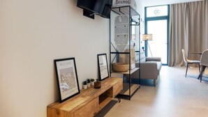 A modern living room with a sofa, a coffee table, a TV mounted on the wall, and a window with curtains. - VLC HOST - Zapadores J (Valencia)