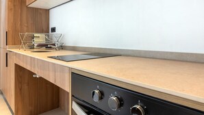 A modern kitchen with wooden cabinetry, a countertop, and a built-in oven. - VLC HOST - Zapadores J (Valencia)