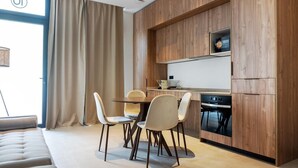 A modern kitchen with wooden cabinetry, a dining area with chairs, and a large window with curtains. - VLC HOST - Zapadores J (Valencia)
