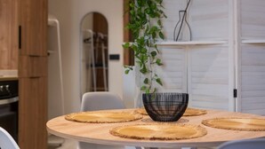 A round wooden table with woven placemats and a black woven bowl in the center.