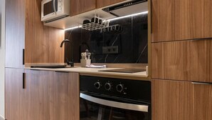 A modern kitchen with wooden cabinetry, a stainless steel range hood, a microwave, and an oven.