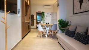 A modern living room with a sofa and a dining area with chairs and a table.