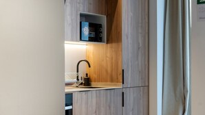 A compact kitchen with a microwave, sink, and wooden cabinets. - VLC HOST - Zapadores I (Valencia)