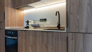A modern kitchen with wooden cabinetry, a built-in oven, a stainless steel range hood, a sink with a faucet, and a drying rack. - VLC HOST - Zapadores I (Valencia)