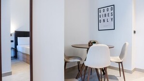 A modern hotel room with a dining area featuring a round table and two chairs, a bed, and a framed motivational quote on the wall. - VLC HOST - Zapadores I (Valencia)