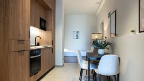 A modern kitchen with wooden cabinets, a built-in microwave, and a stove. There is a dining area with a table, chairs, and a potted plant. - VLC HOST - Zapadores E (Valencia)