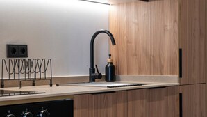 A modern kitchen with wooden cabinets, a black faucet, and a built-in oven. - VLC HOST - Zapadores E (Valencia)