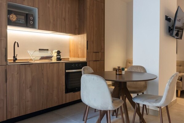 A modern kitchen with wooden cabinets, a built-in oven, and a dining area with a round table and four chairs. - VLC HOST - Zapadores D (Valencia)