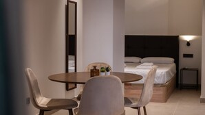 A modern bedroom with a large bed, bedside table, and a small table with chairs in the foreground. - VLC HOST - Zapadores B (València)