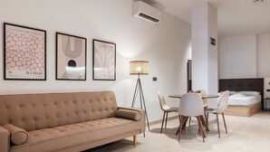 A modern hotel room with a beige sofa, a dining table with chairs, and artwork on the walls. - VLC HOST - Zapadores B (València)