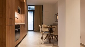 A modern kitchen with wooden cabinets and a built-in oven, leading to a dining area with a table and chairs. - VLC HOST - Zapadores B (València)