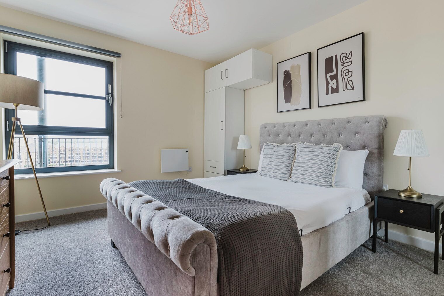 Une chambre à coucher avec un grand lit, une table de chevet, une lampe, une armoire et une fenêtre donnant sur un beau paysage.