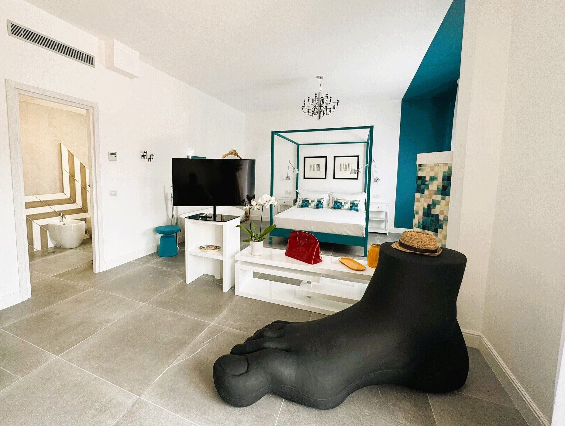 Un salon moderne avec un grand téléviseur, un canapé et un pouf noir original en forme de pied.