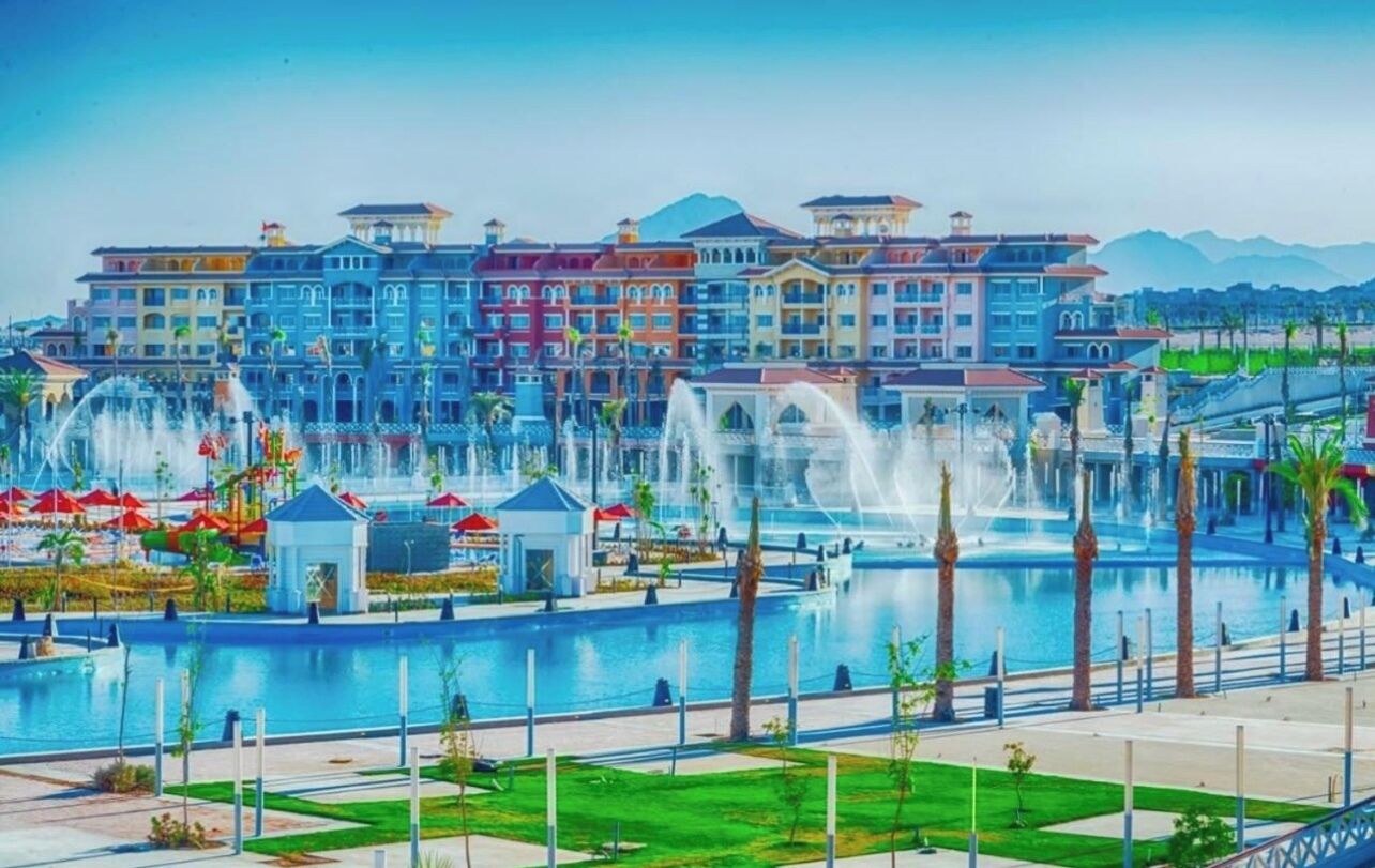 A hotel with a large fountain, multiple balconies, and a pool area.