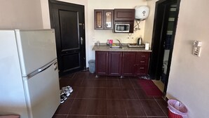 Una cocina compacta con refrigerador, microondas, pileta y alacenas.